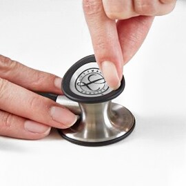 Fingers removing the tunable diaphragm from the bell of a 3M Littmann Classic III Stethoscope.