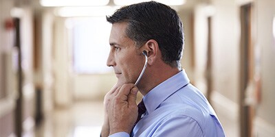 Un clinicien plaçant les embouts auriculaires d’un stéthoscope dans ses oreilles.
