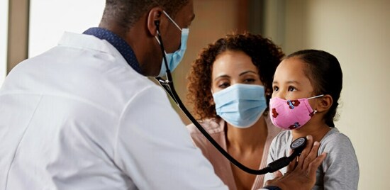 Un médecin plaçant le pavillon d’un stéthoscope sur le cœur d’un enfant.
